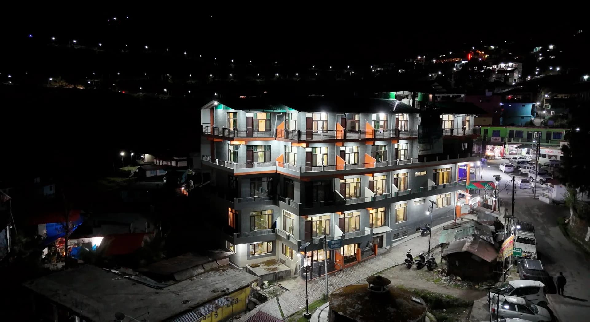 Hotel Leela Mount View lit up at night — aerial shot